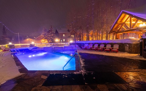 a view of the outdoor pool at night while it is snowing