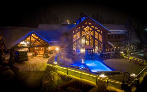 a view of the pool and lodge at night with fog near the pool