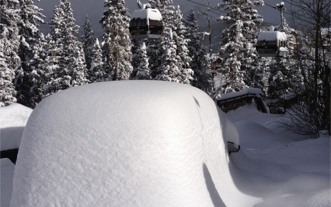thick snow covering cars and the gondola