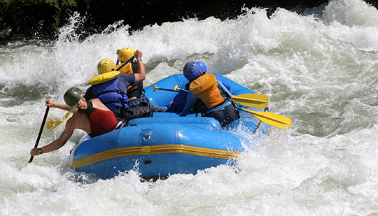 a group of people white water rafting in a blue boat