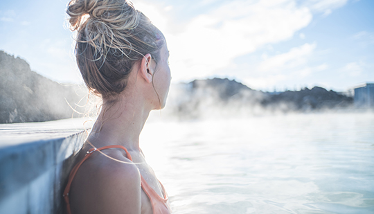 a woman in the hot spring with steam rising from the water