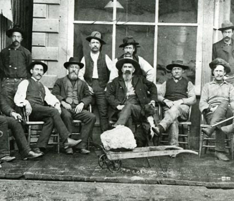 a black and white image of men sitting in front of a building