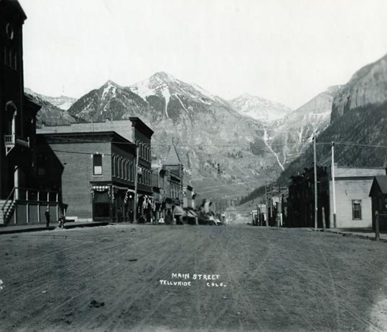 a black and white image of main street in a small town