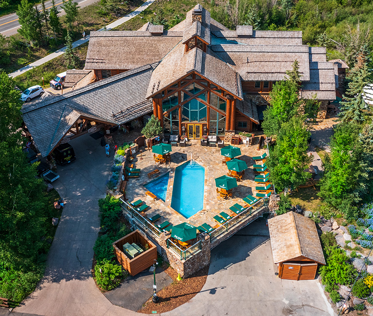 a drone shot of the main building of the property and the pool deck during the day