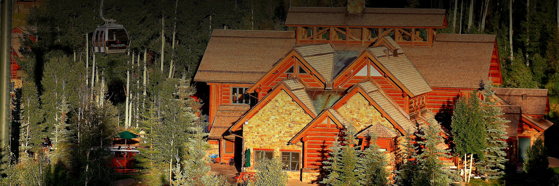 the exterior of the lodge with stone and red wood at sunset