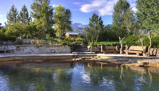 a hot spring with a wooden bench to sit next to it