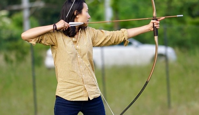 Female archer pulling back bow and arrow