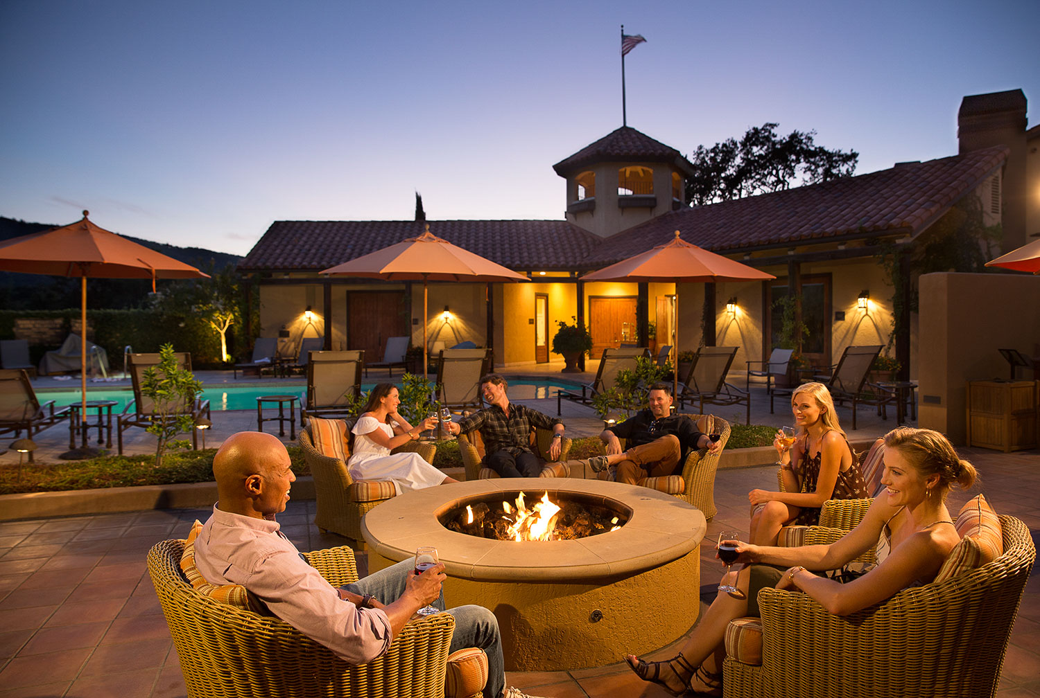 A group of people gathering by the courtyard fire pits at night