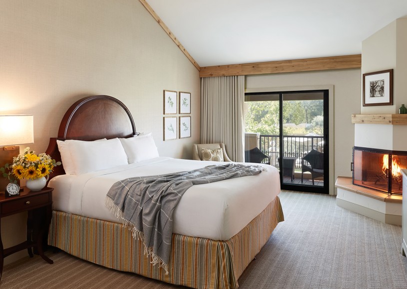 Internal view of a room with a large bed, a fireplace and a private balcony