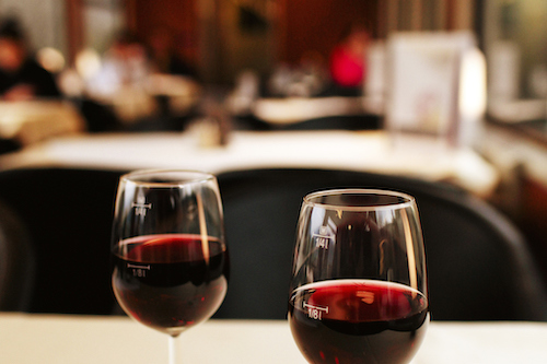 two glasses of red wine on white cloth covered table