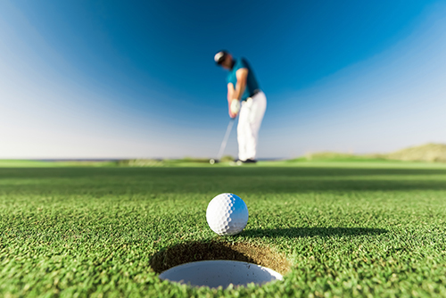 close up shot of a man playing golf and making the shot 