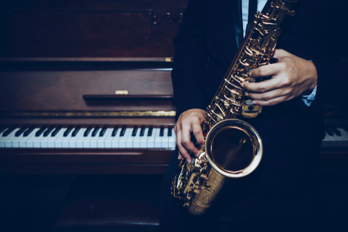 saxophone player in front of a piano