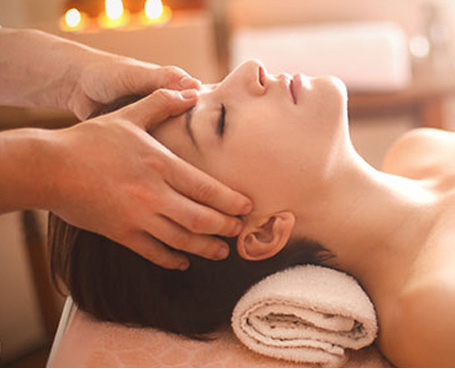 woman laying down getting a massage hands on her forhead Image
