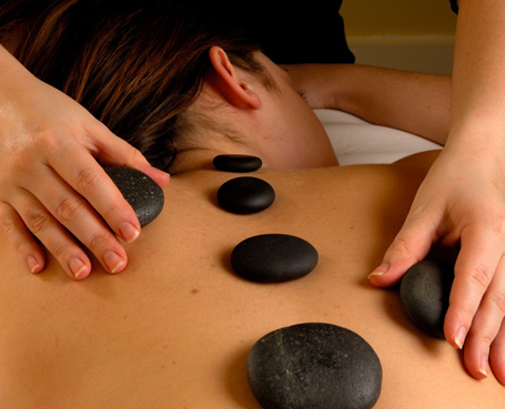 woman receiving back massage with six black stones on her back Image