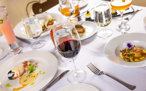 close up view to a table with plates with the preferred dishes and glasses with drinnks