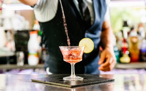bartender pouring liquid on a cocktail glass