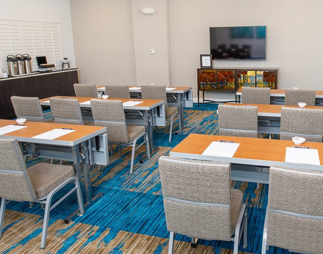 two person conference tables set for a meeting facing a tv