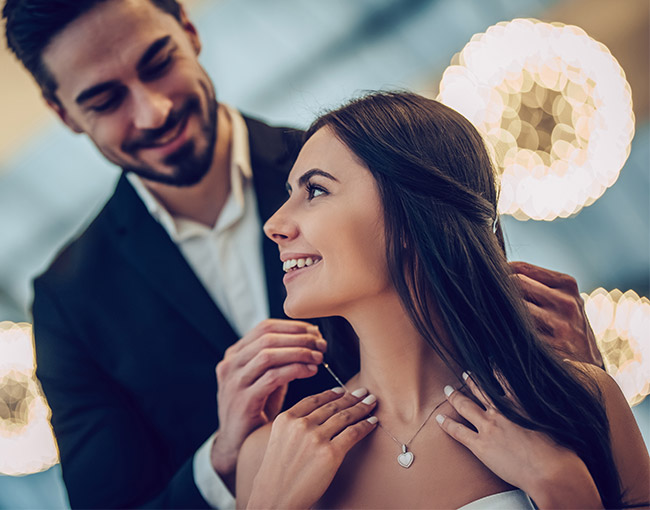 a man putting a necklace around a woman's neck