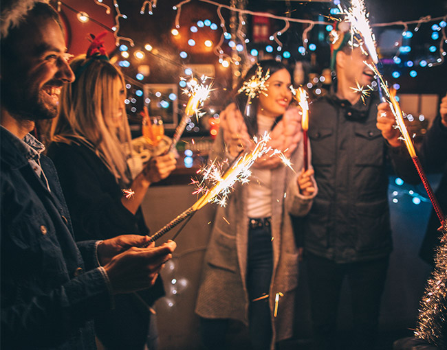 a group of friends holding sparklers at night