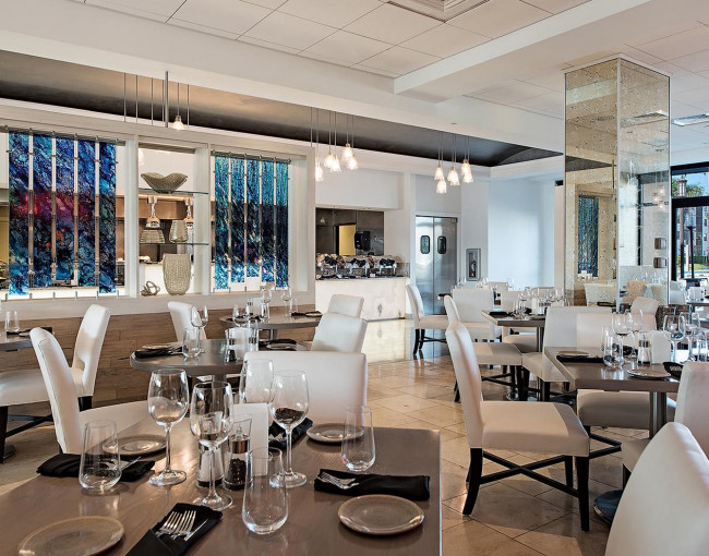 restaurant dining area with white leather chairs, and tables set for dinner