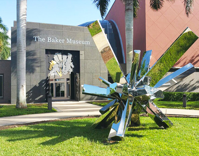a large silver metal sculpture in the lawn in front of a museum building