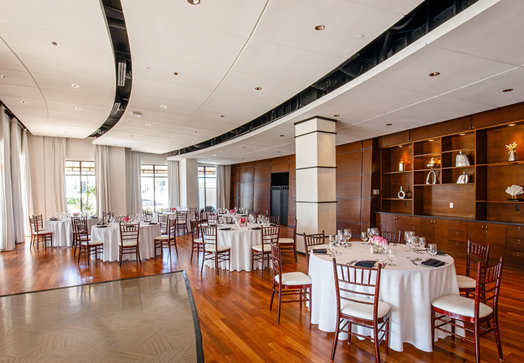 A event space decorated for elegant dining with round white tablecloth tables and chairs