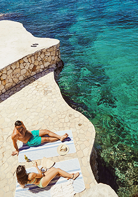 Aerial view of a couple tanning and relaxing on a cliff