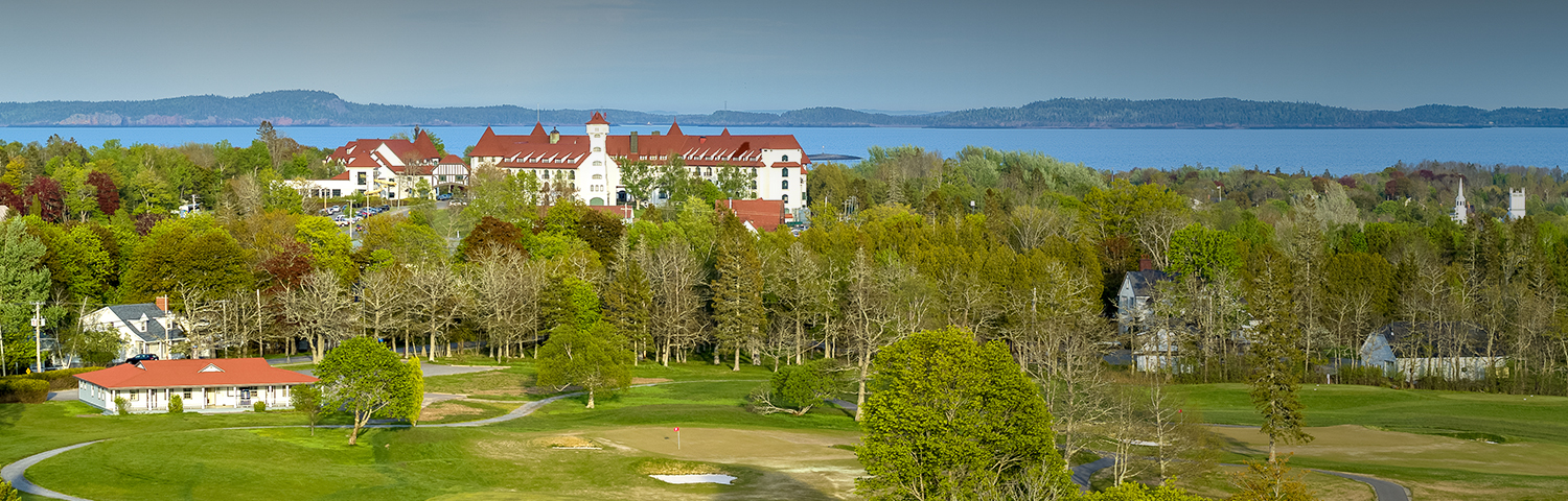 Aerial of a green golf coarse with large white hotel in the background