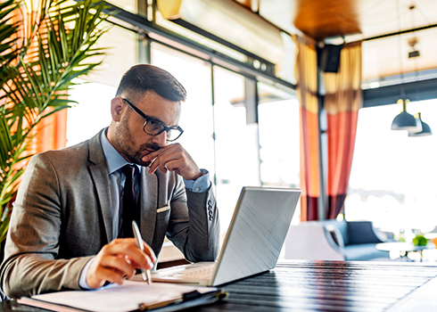 Man with grey suit and glasses working on a computer