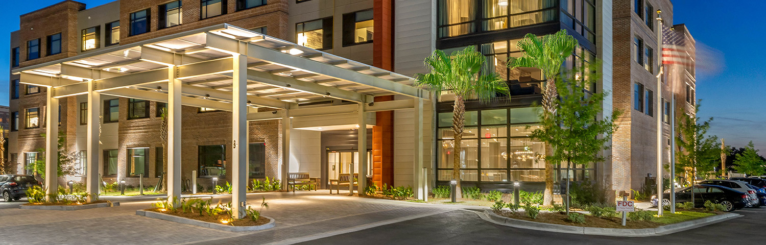 Large white Hotel with orange accents entrance with palm tree 