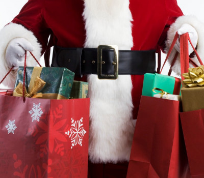 Shopper in Santa Claus Costume Holds Many Gift Wrapped Packages in Holiday Bags