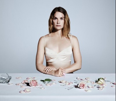 woman sitting at a table with flower pedals and broken glass