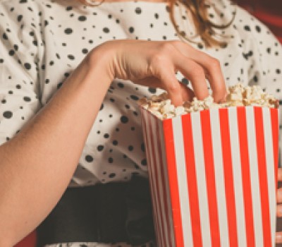 woman sitting in a movie with her hand in a popcorn bag