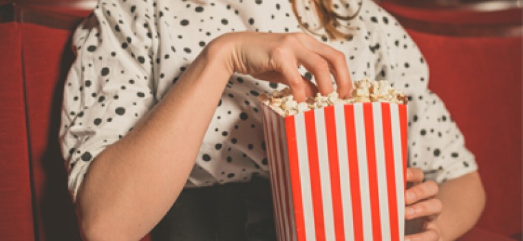 woman sitting in a movie with her hand in a popcorn bag