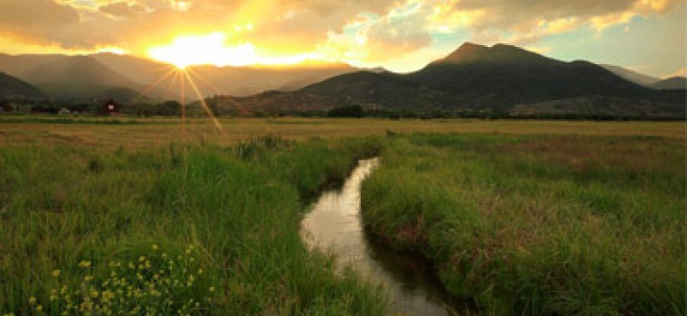 rural utah with the sun shining behind the mountains