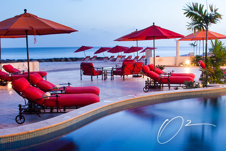 red beach lounge chairs next to pool and by the beach
