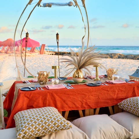 bubble on the beach with pillows, small dining table, and lanterns