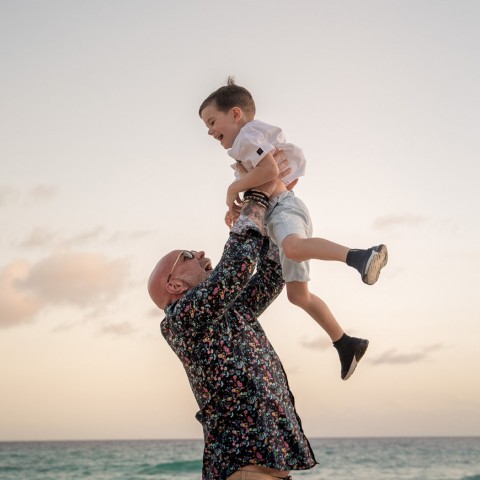 man holding kid up over his head