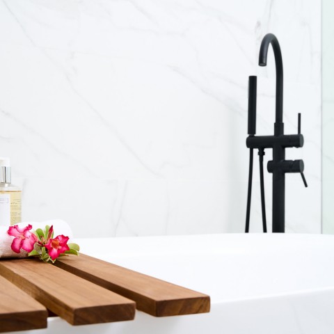 bathtub with wooden tray across it and black faucet