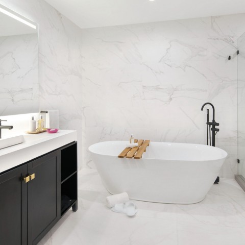 marble bathroom with white rub and black cabinets