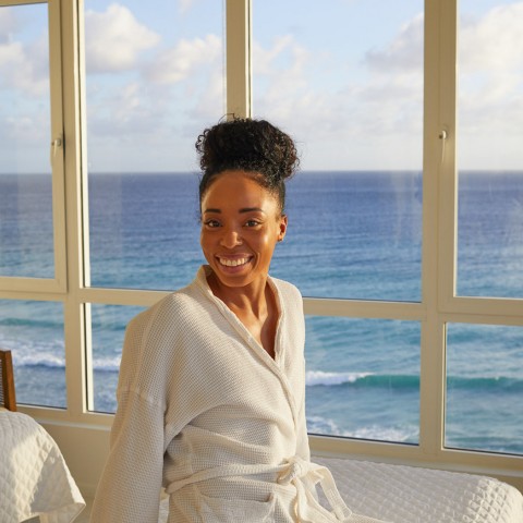 woman smiling in robe with ocean in the background