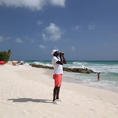 man blowing conch shell on the beach