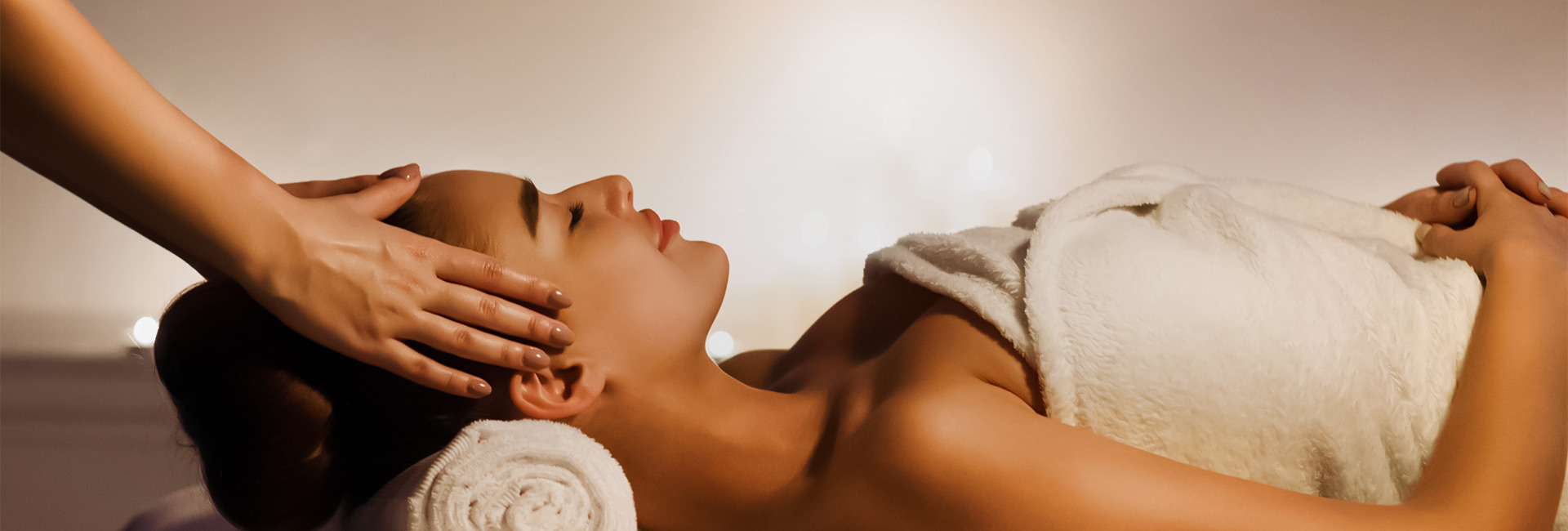 woman wrapped in towel getting massage around her temples