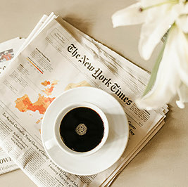 cup of black coffee sitting on new york times news paper 