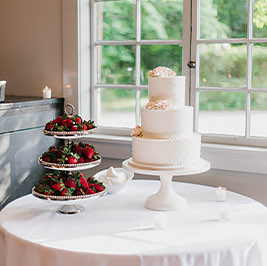 small wedding cake with trays of strawberries beside it 