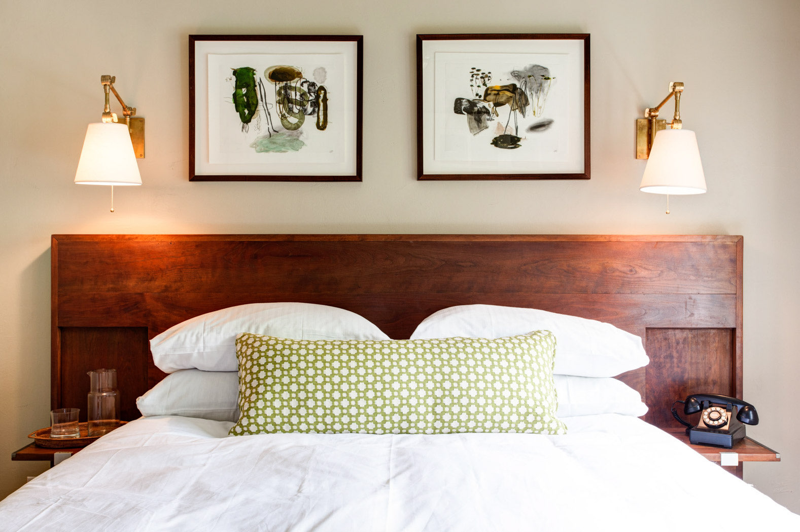 close up of bed with oak head board and green and white pillow 