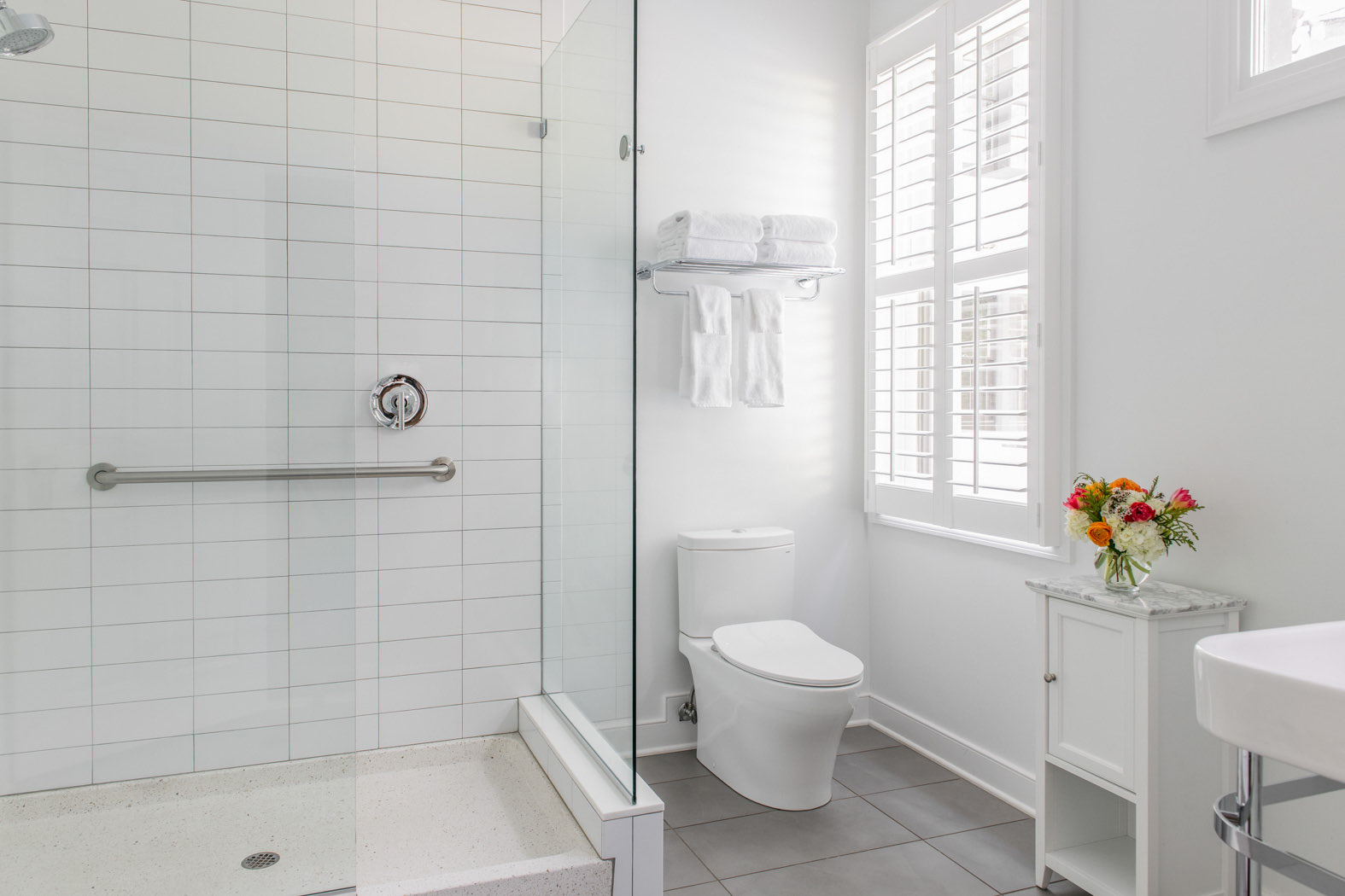 walk in accessible shower with towel rack and toilet 