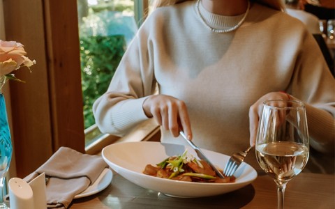 Woman eating a meal with wine
