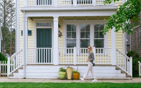 Woman walking in front of a yellow house