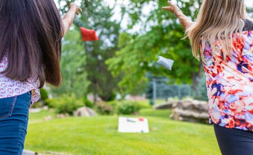 two girls playing a game of bean bag toss